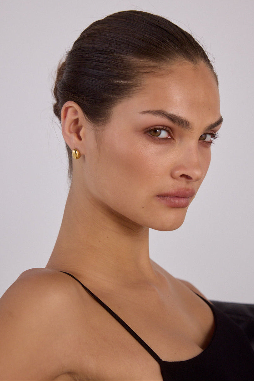 Close-up detail of the Cendré Bean gold earring curves