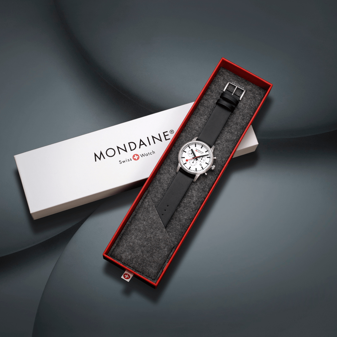Mondaine wristwatch with a black leather strap in a red-trimmed presentation box.