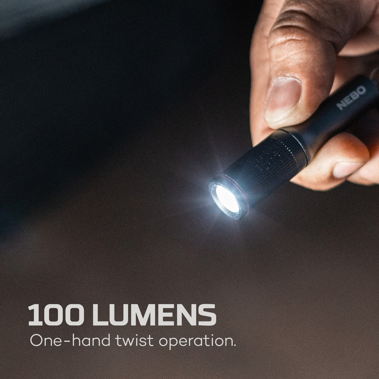 Compact flashlight with a bright beam being operated by a hand.