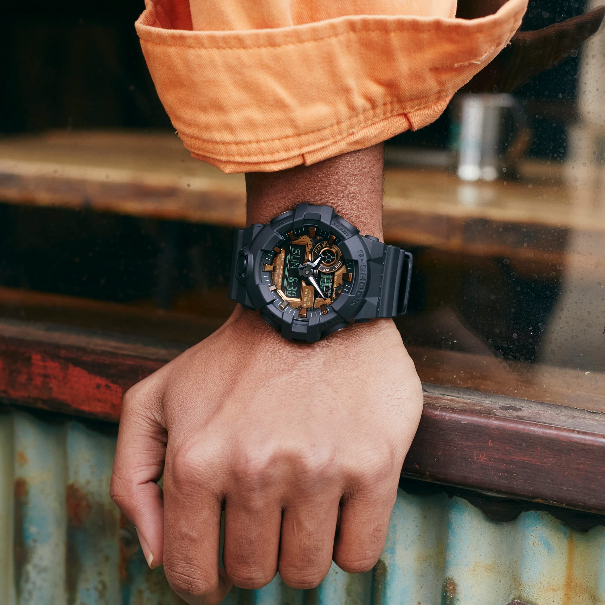 Rugged black and gold wristwatch with a digital display worn on a person’s wrist.