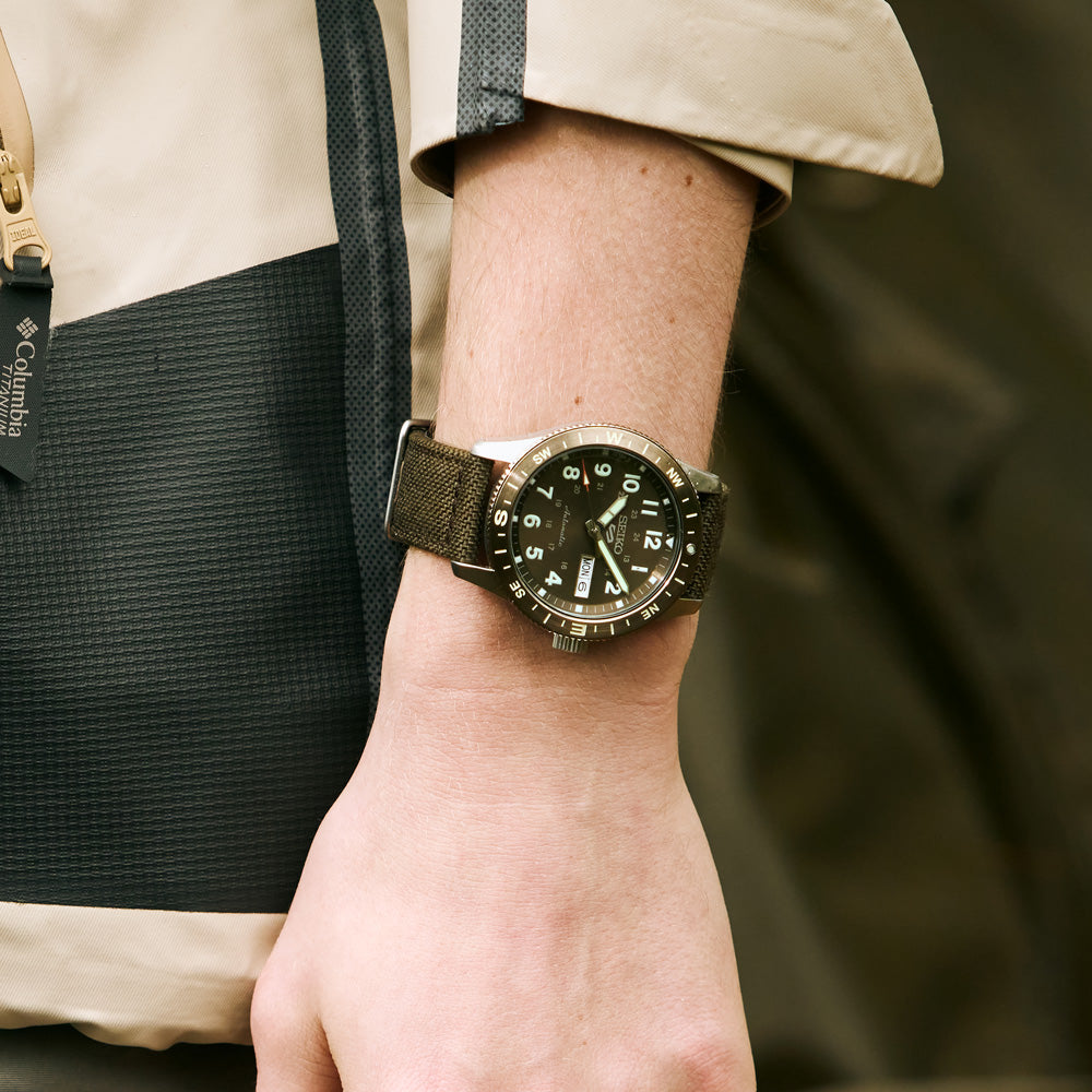Close-up of the Seiko HDB009K brown dial with luminous numerals and compass bezel.