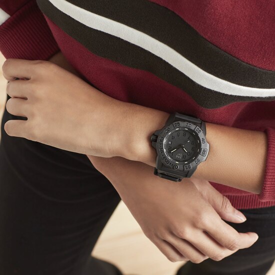Black wristwatch with a round face worn on a person’s wrist.