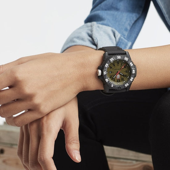 Rugged wristwatch with a green dial and black bezel worn on a person’s wrist.