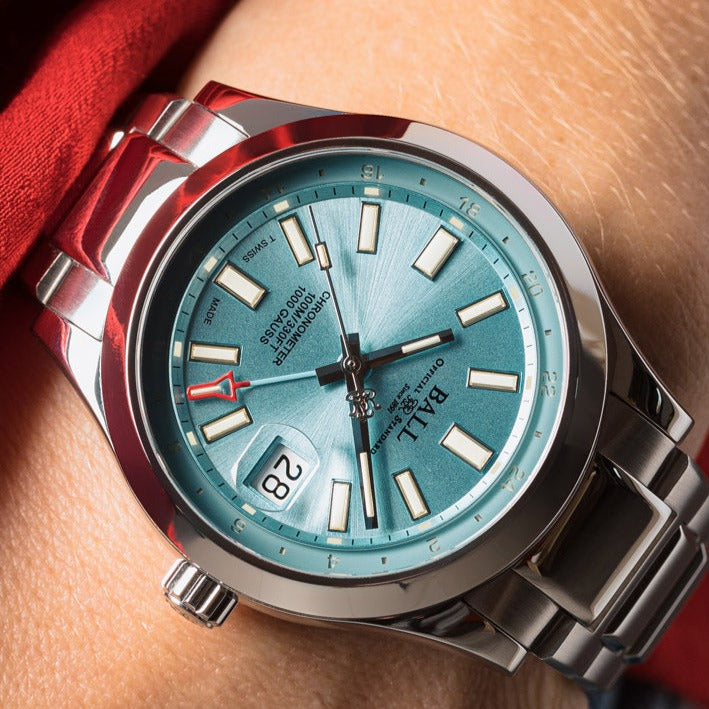 Stainless steel wristwatch with a teal-colored dial and date window.