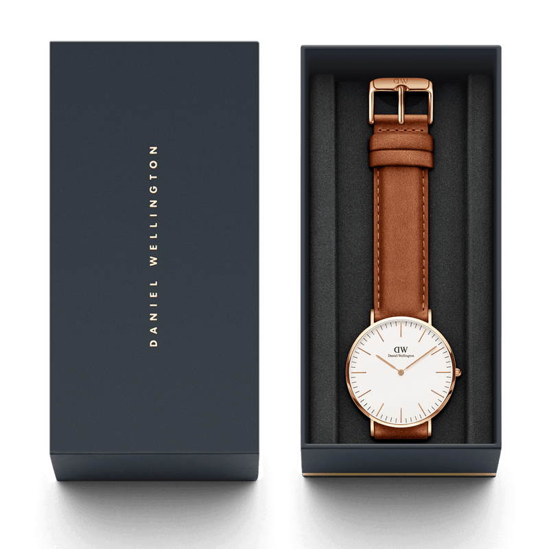 Wristwatch with a brown leather strap and white face in a presentation box.