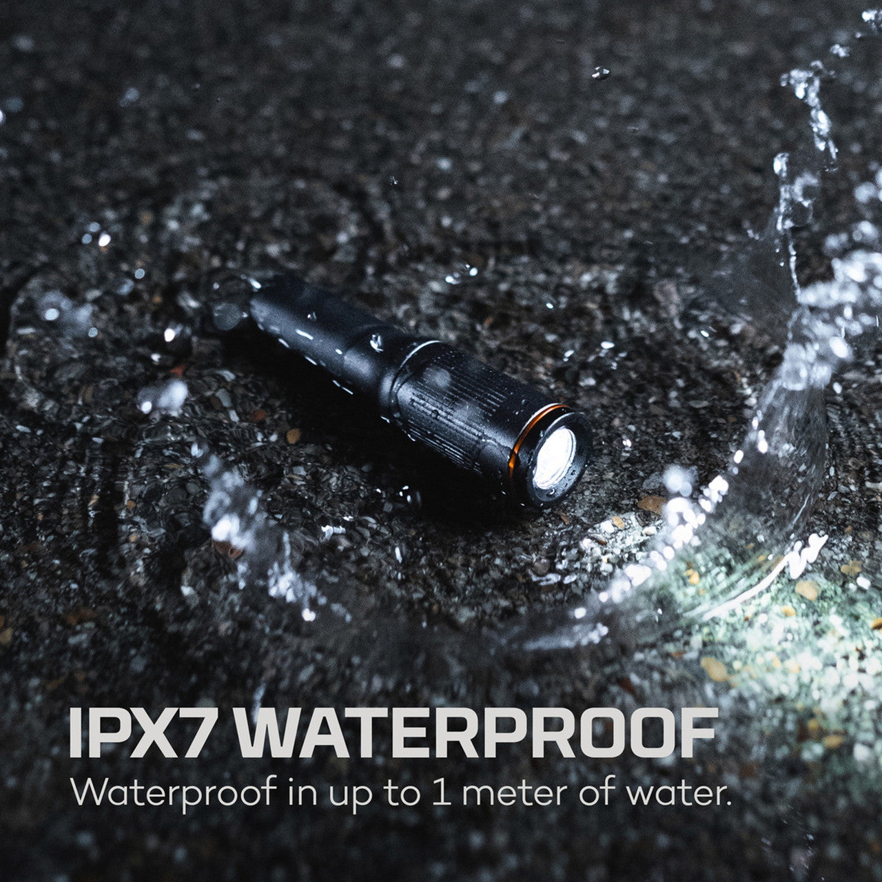 Black waterproof flashlight with water splashing around it.