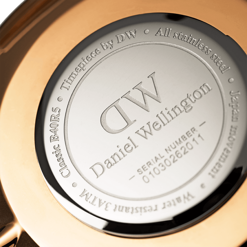 Engraved metal watch case back displaying the Daniel Wellington logo and product details.