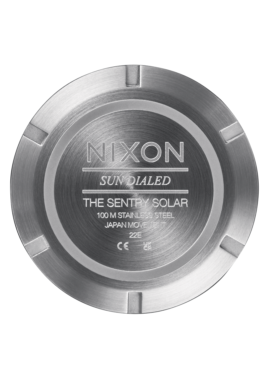 Circular metal watch case back with engraved text for a Nixon Sentry Solar watch.