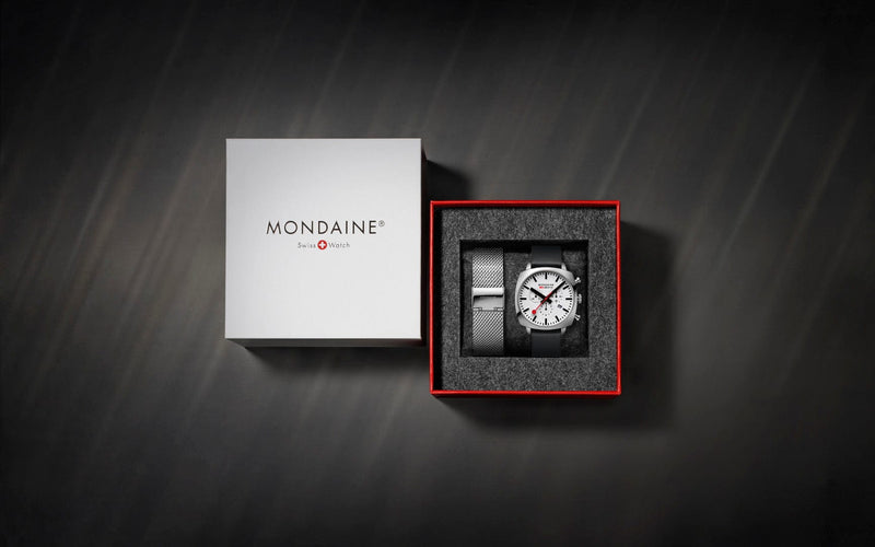 Wristwatch in an open gift box with ’MONDAINE’ branding on the lid.