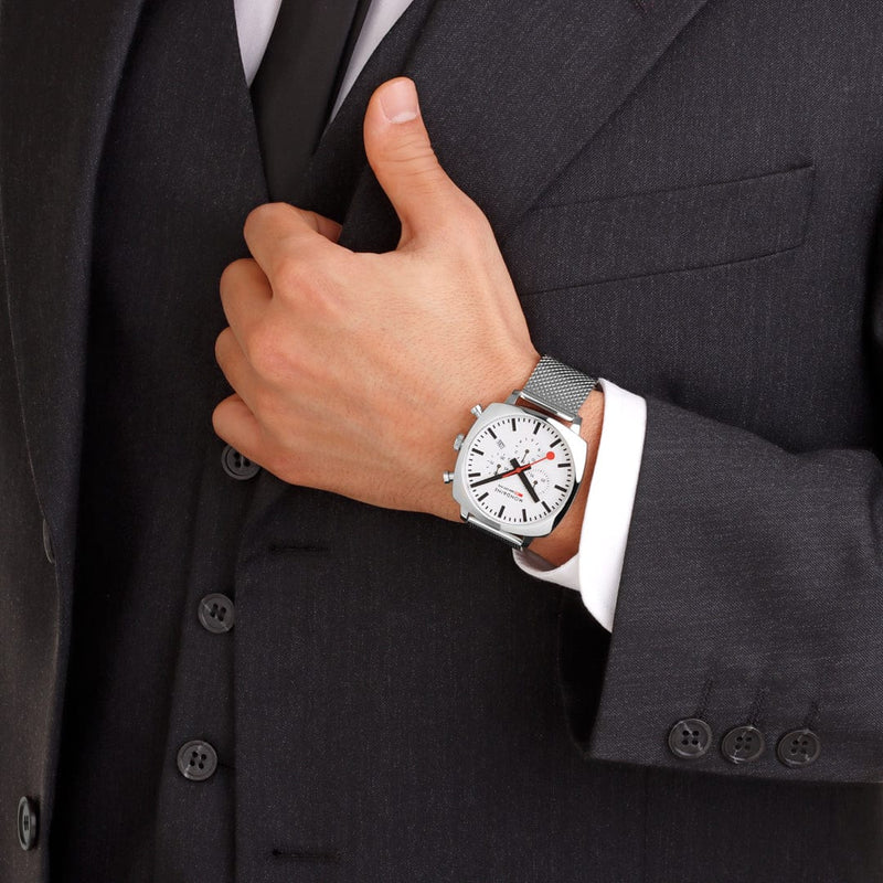 Wristwatch with a white face and metal bracelet worn on a person’s wrist.