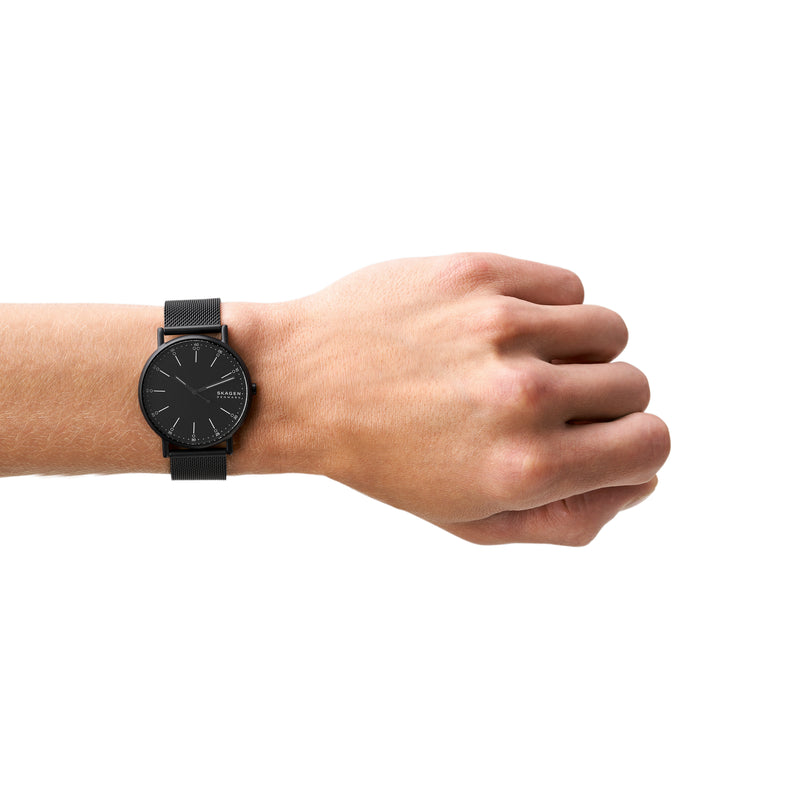 Black wristwatch with a minimalist round face worn on a person’s wrist.