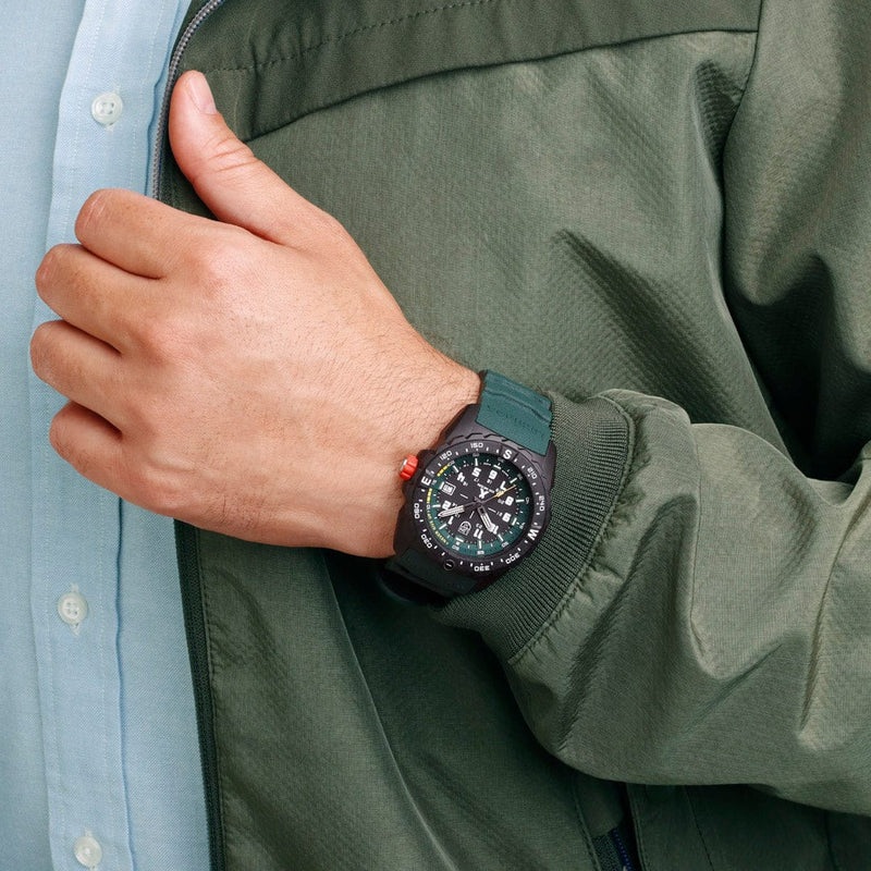 Wristwatch with a black face and green strap worn on a person’s wrist.