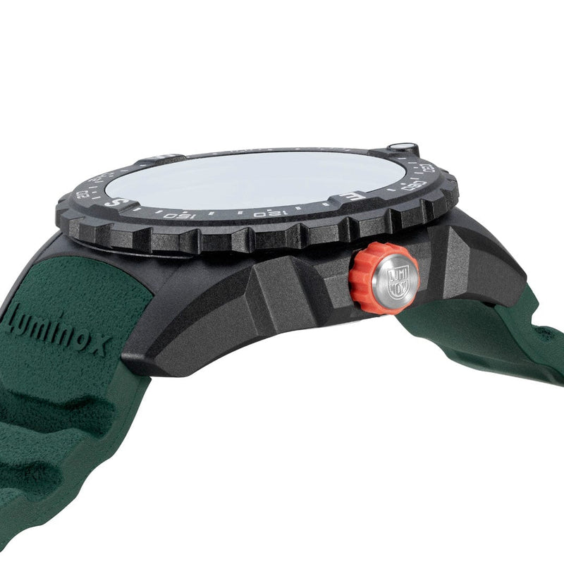 Wristwatch with a dark bezel and green strap, featuring a red button on the side.