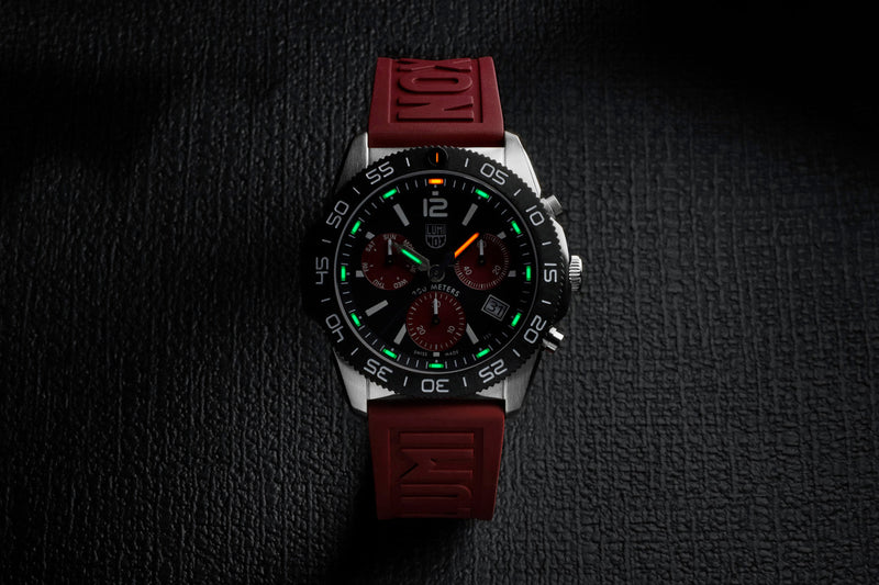 Stylish wristwatch with a red strap and black dial featuring luminous green accents.