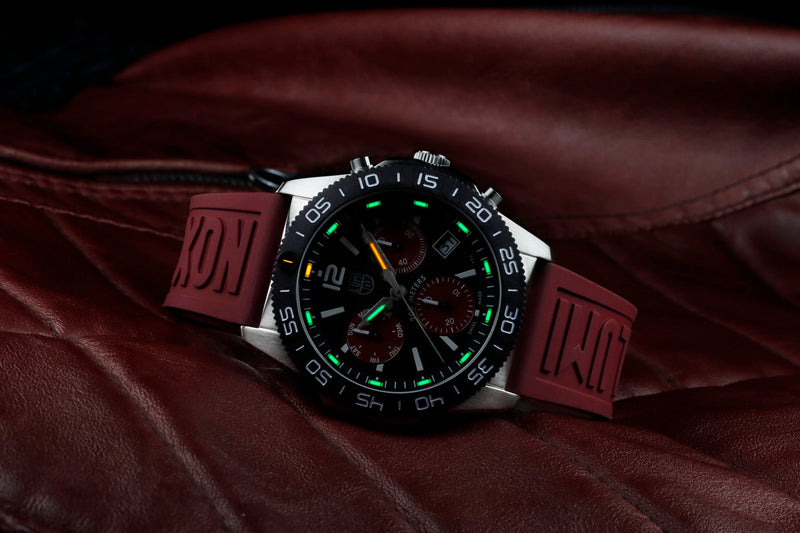 Stylish sports watch with a black dial and green accents on a red rubber strap.