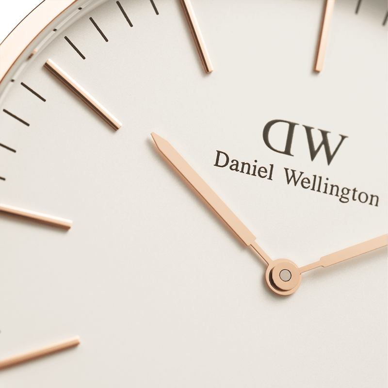 Close-up view of a Daniel Wellington watch face with rose gold hands and hour markers.