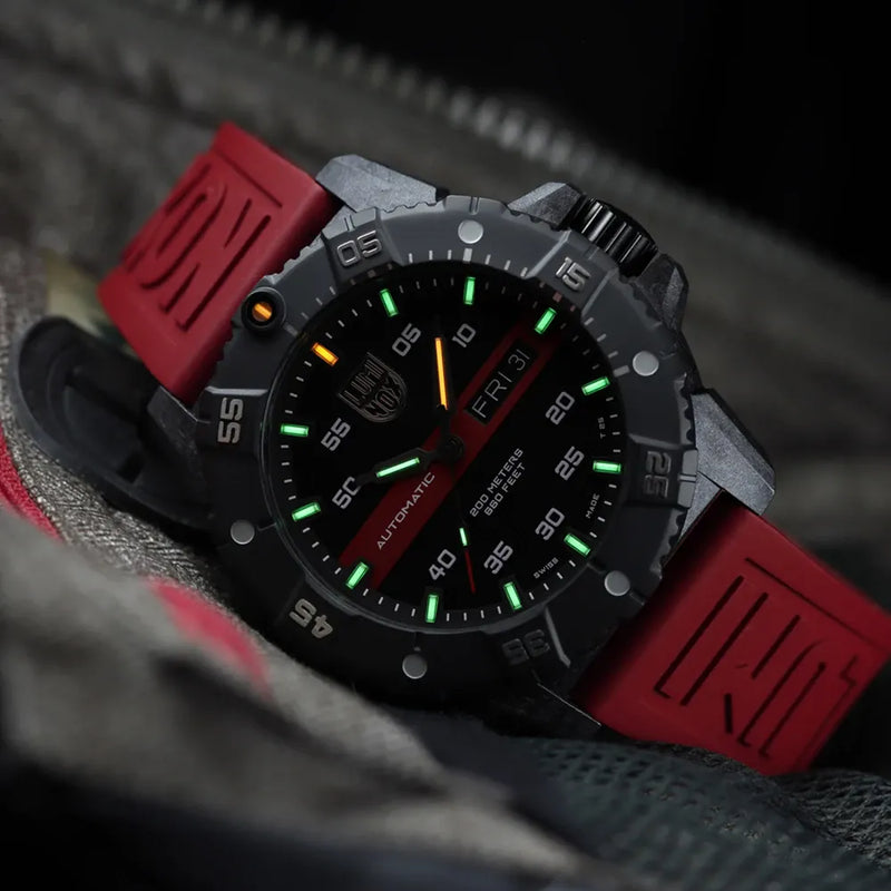 Rugged sports watch with a black face, red strap, and luminous markings.