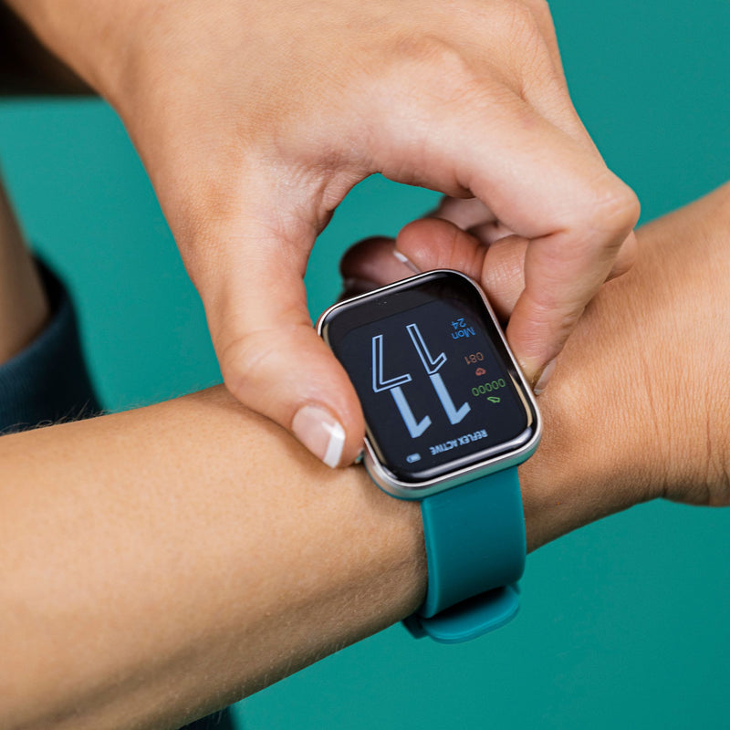 Smartwatch with a teal band being adjusted on a person’s wrist.