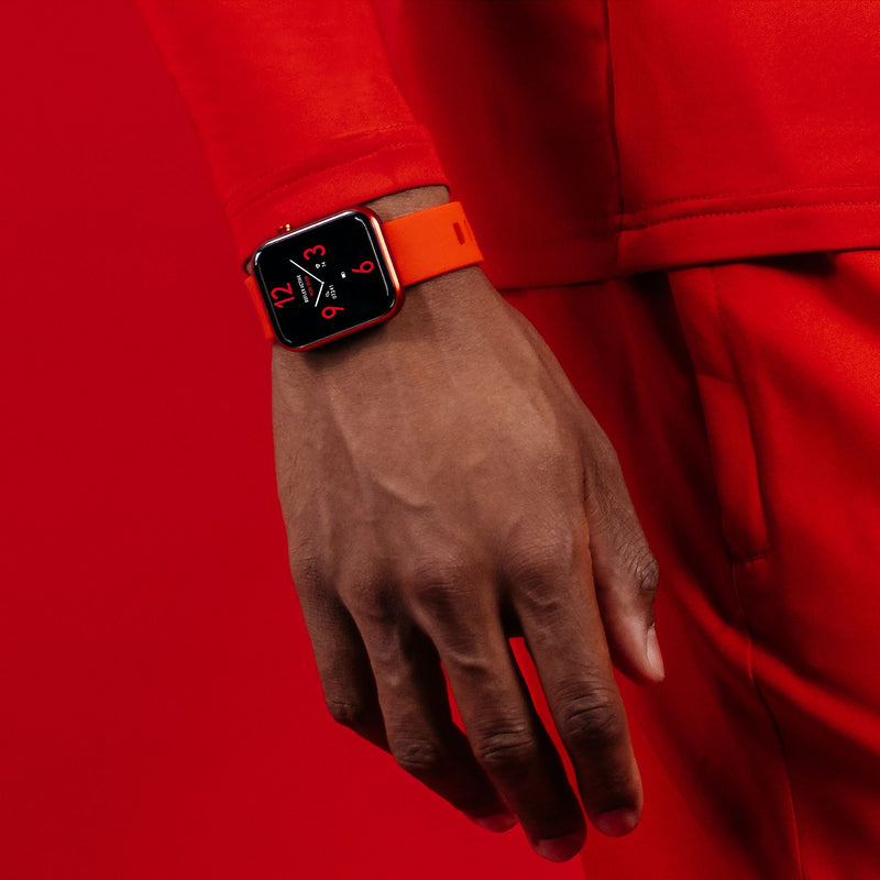 Smartwatch with an orange band worn on a person’s wrist.