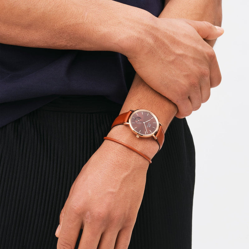 Elegant wristwatch with a round brown face and slim gold-toned band.