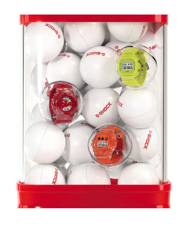 Container filled with white ping pong balls and colorful digital watches.