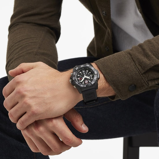 Black sports watch with a round face and multiple dials worn on a person’s wrist.