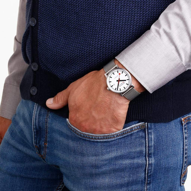 Wristwatch with a round white face and metal mesh band.