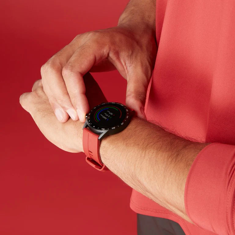 Smartwatch with a round face and red strap worn on a person’s wrist.