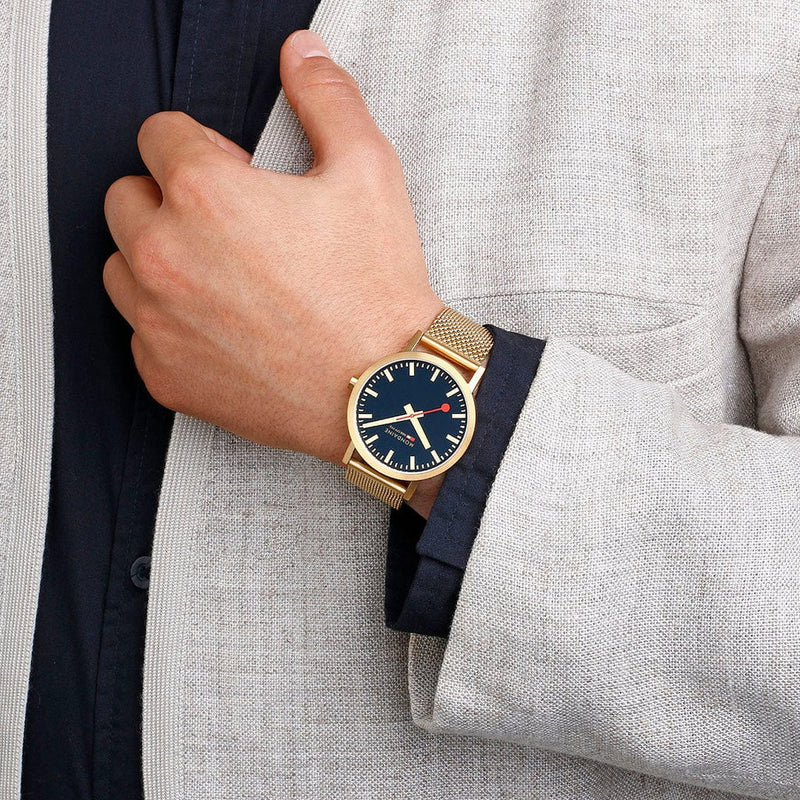 Gold wristwatch with a blue face and mesh metal band.