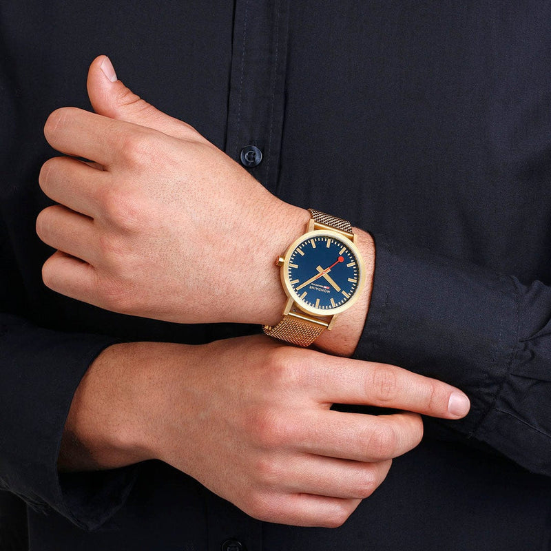 Gold wristwatch with a blue dial face and mesh metal band.