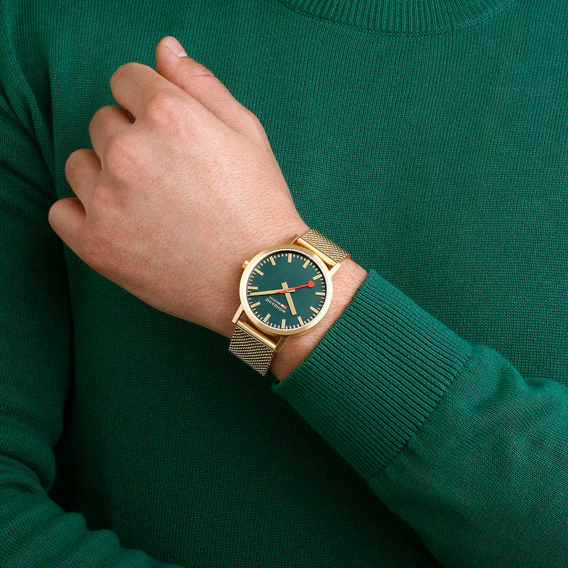 Gold wristwatch with a green dial and mesh metal band.