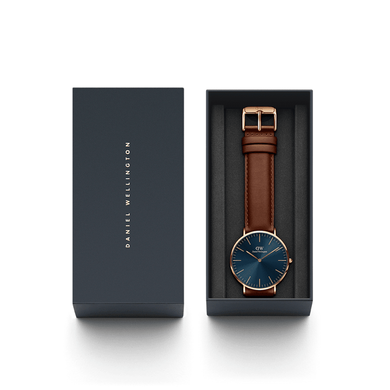 Wristwatch with a blue face and brown leather strap in a presentation box.