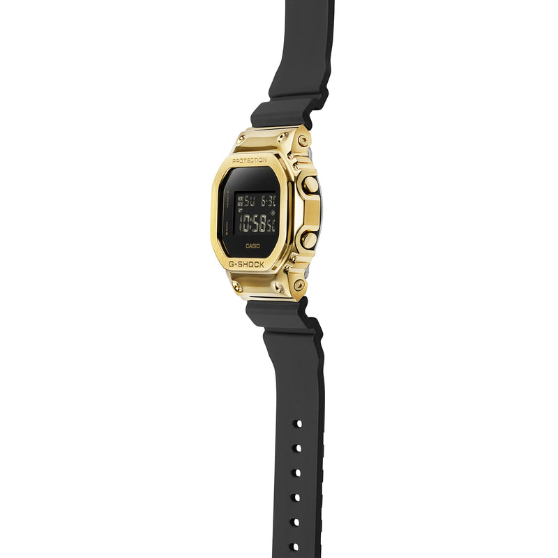 Gold-toned digital wristwatch with a black rubber strap.