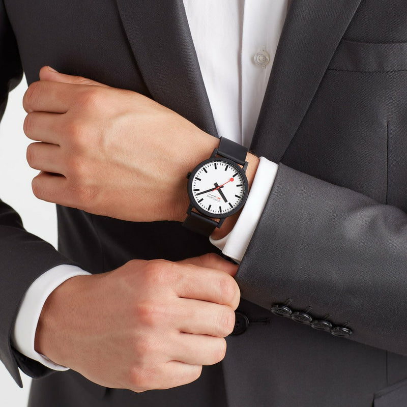 Wristwatch with a white face and black strap worn on a person’s wrist.