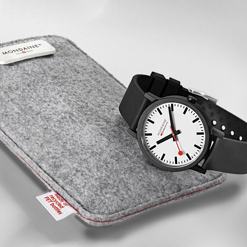 Analog wristwatch with a black strap on a gray felt sleeve.