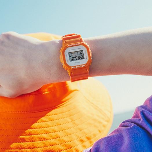 Orange digital wristwatch with a square face displaying the time.