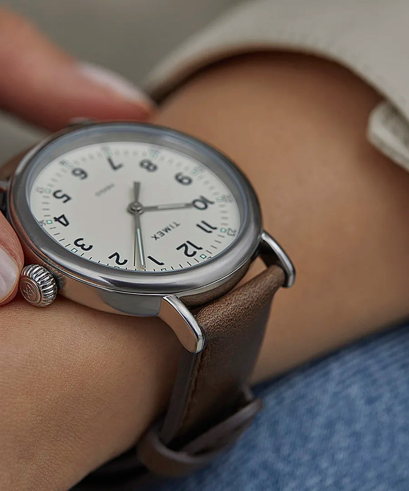 Analog wristwatch with a round face and brown leather strap.