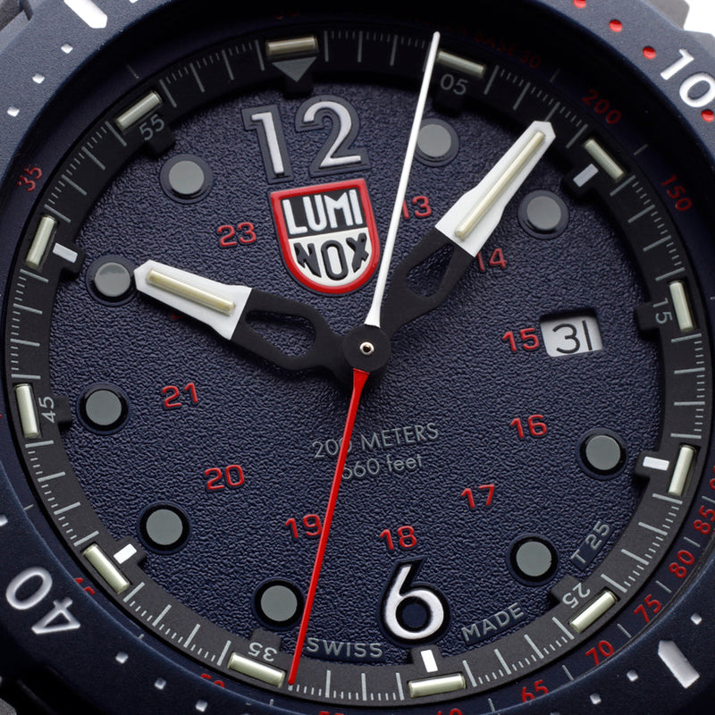 Close-up of a Luminox wristwatch face with a dark blue dial and red accents.