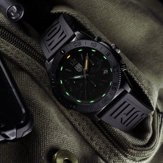 Black tactical wristwatch with luminous green markings on a dark dial.