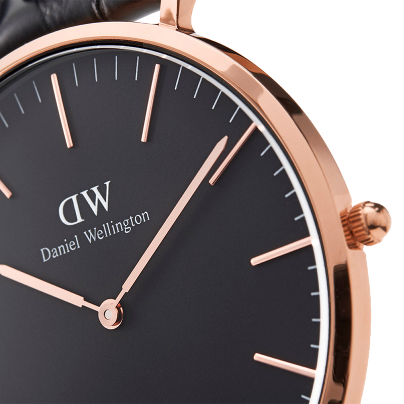 Elegant wristwatch with a black face and rose gold accents, displaying the brand ’Daniel Wellington’.